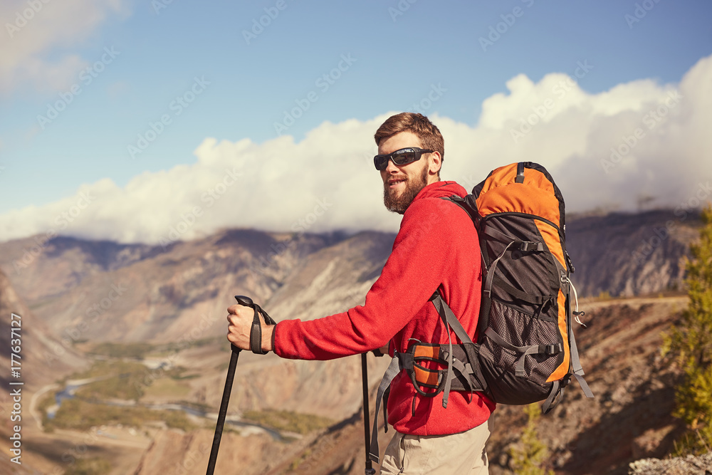 Handsome young bearded male hiker standing on the edge of a canyon looking away