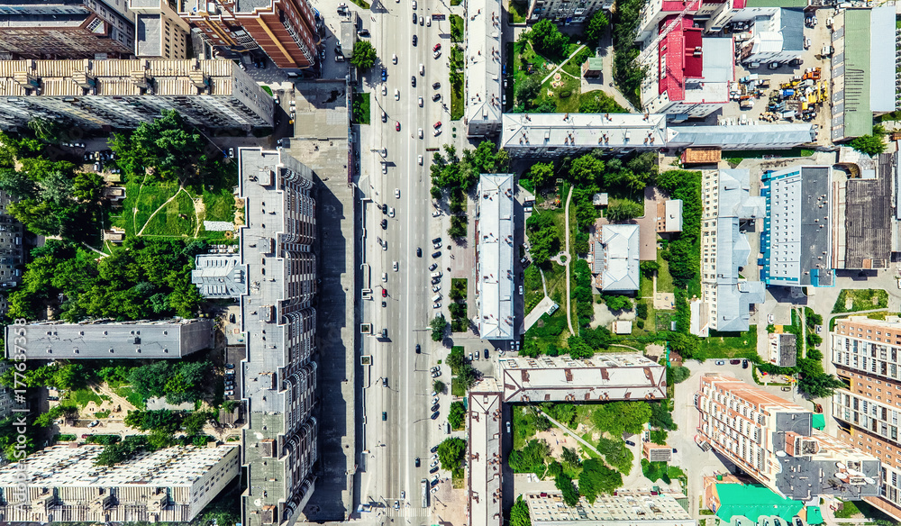 Fototapeta premium Aerial city view with crossroads and roads, houses, buildings, parks and parking lots, bridges. Helicopter drone shot. Wide Panoramic image.