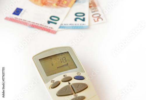 Remote Control for air conditioning and money on a white background