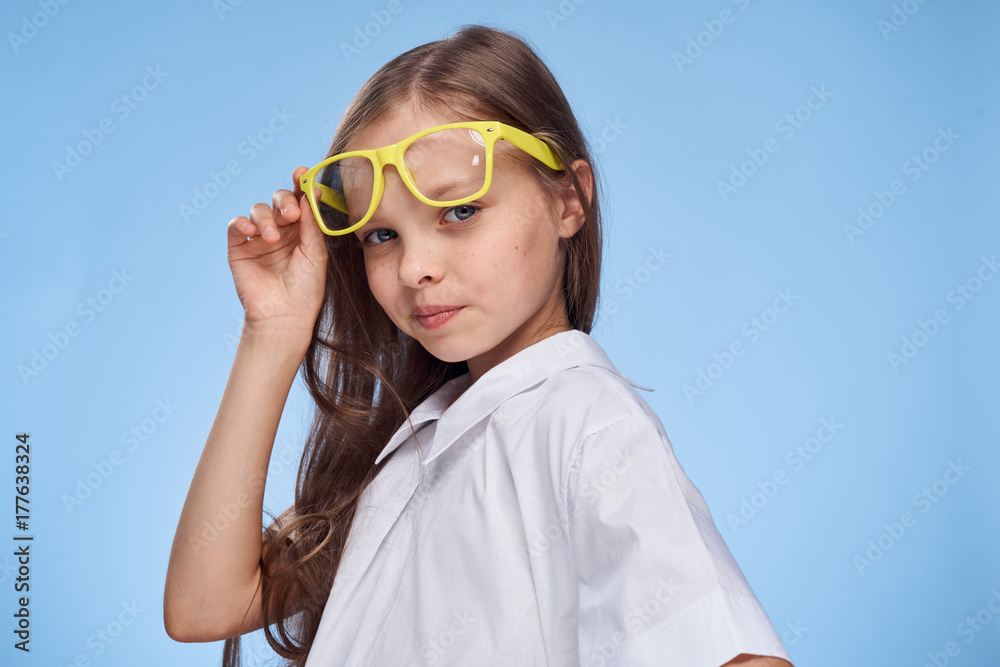 little schoolgirl girl looking at the camera on a blue background, school, school, glasses, knowledge