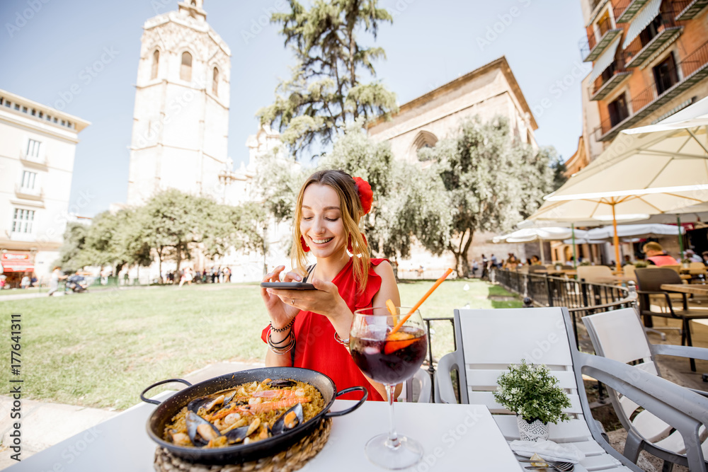 Φωτογραφία Young woman in red dress photographing sea Paella, traditional Valencian rice di
