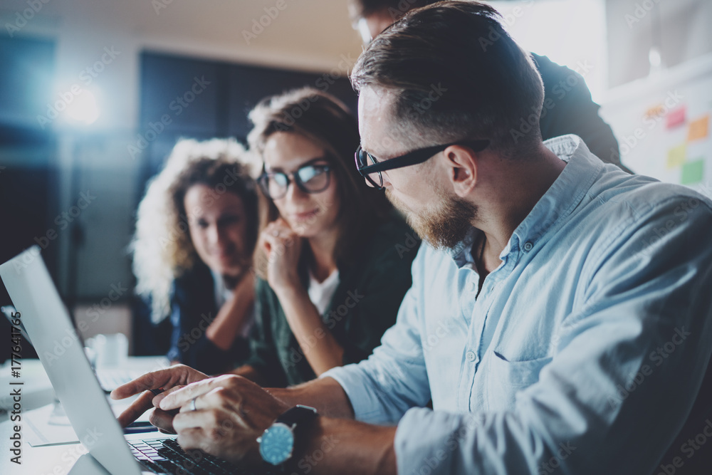 Concept of teamwork process at office.Young team working together at night modern office loft.Blurred background.Horizontal. Concept of teamwork process at office.Young team working together at night modern office loft.Blurred background.Horizontal.