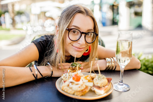 Young woman enjoying tasty appetizer with pinchos  traditional spanish snack  and glass of wine sitting outdoors at the bar in Valencia city