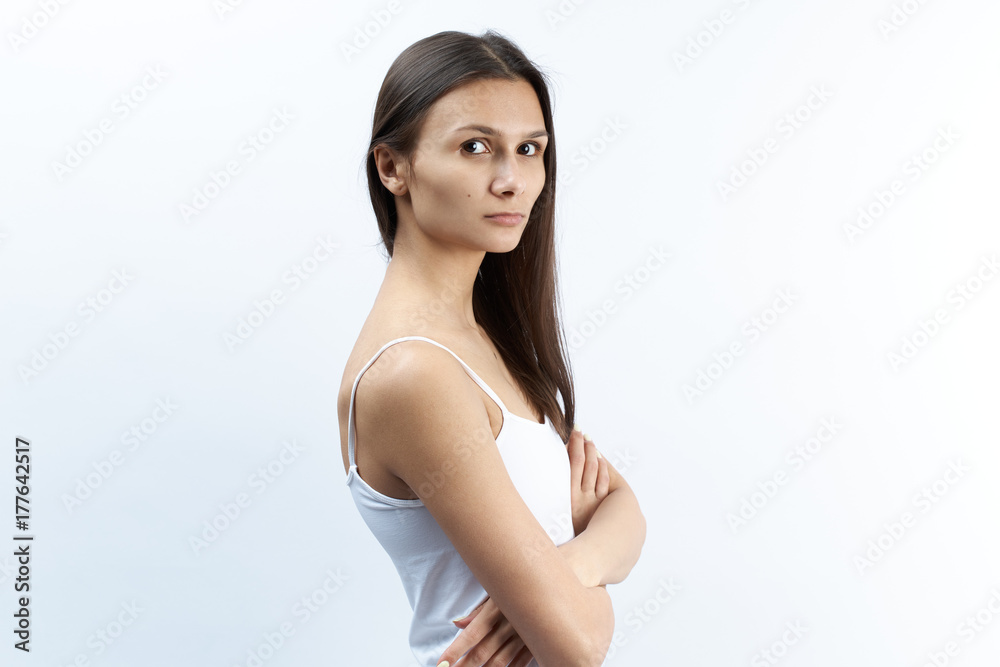 Studio portrait of young Caucasian woman with serious upset dissatisfied with a puzzled expression. arms crossed over the abdomen. Studio portrait of young Caucasian woman with serious upset dissatisfied with a puzzled expression. arms crossed over the abdomen.