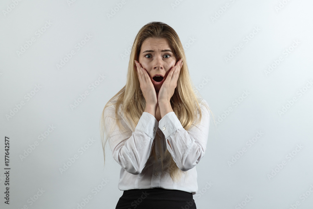 businesswoman dressed in business style clothing posing for a portrait with a terrified shocked expression stress. Long hair, hands pressed against cheeks, mouth open. businesswoman dressed in business style clothing posing for a portrait with a terrified shocked expression stress. Long hair, hands pressed against cheeks, mouth open.
