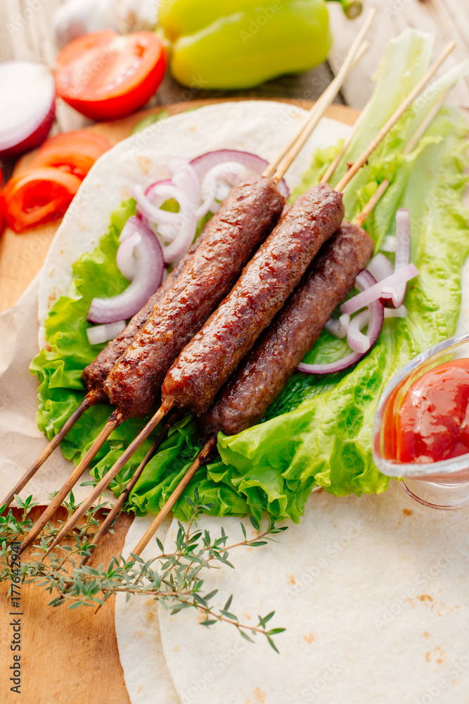 Fast food. Eastern food. Shish kebab, lyulya-kebab, shaverma, pita gyros. Dishes of oriental cuisine lying on pita bread and decorated with greens and vegetables, sauces and French fries. 