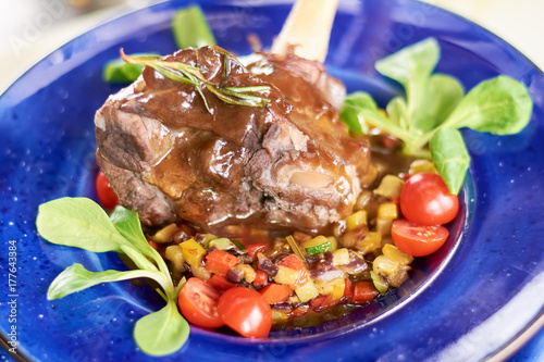 Lamb shank with vegetables ratatouille. Beutifully served with fresh vegetables appetizing lamb shank close up. Delicious european cuisine. photo