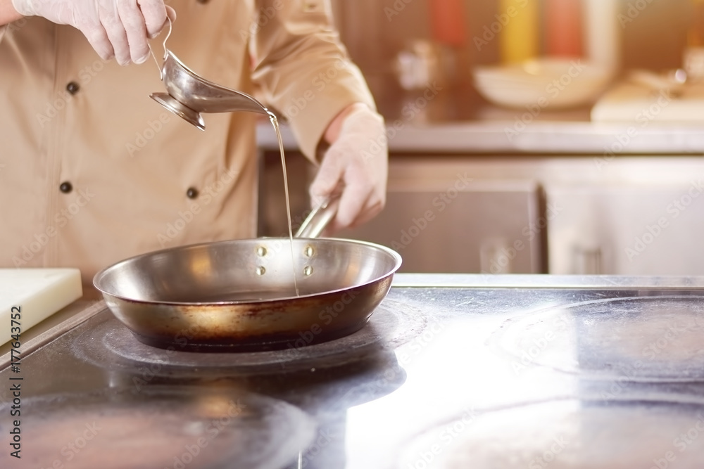 Chef pouring oil in frying pan. Male chef in gloves going to fry duck breast. Cook preparing meat. Chef pouring oil in frying pan. Male chef in gloves going to fry duck breast. Cook preparing meat.