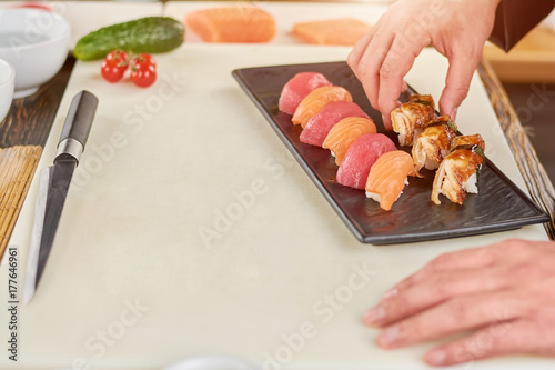 Chef hands placing nigiri sushi on plate. Chef coked nigiri sushi with salmon, tuna and eel. Restaurant of japanese food.