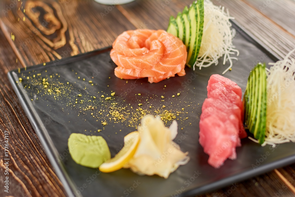 Raw salmon and tuna served with cucumber. Salmon and tuna raw sashimi on traditional japanese dish. Raw salmon and tuna served with cucumber. Salmon and tuna raw sashimi on traditional japanese dish.