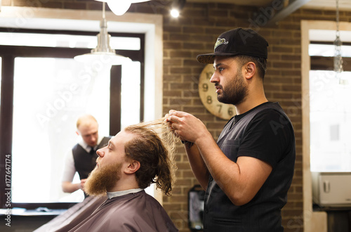 Man getting stylish haircut by hairstylist at barbershop