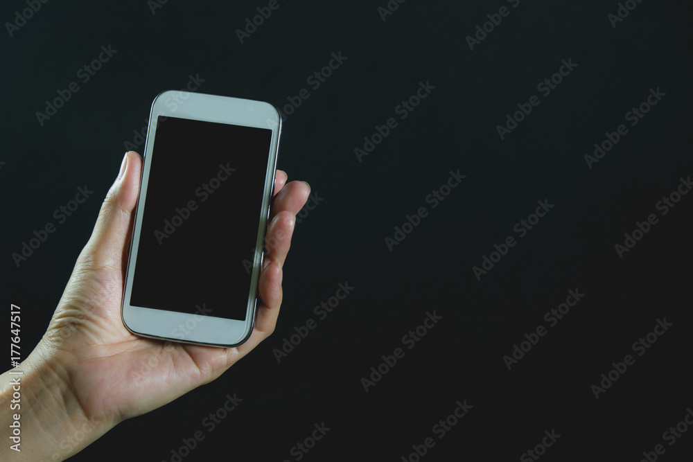 Woman hand holding smart phone isolated on dark background. Woman hand holding smart phone isolated on dark background.
