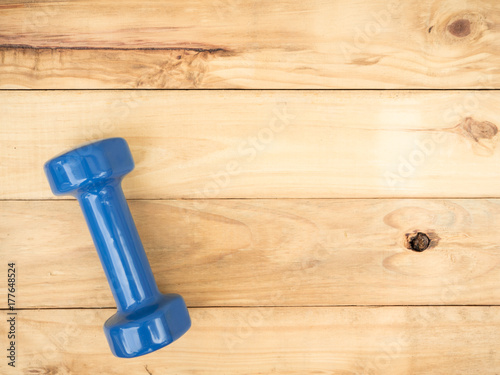blue dumbbell isolated on wooden background with copy space