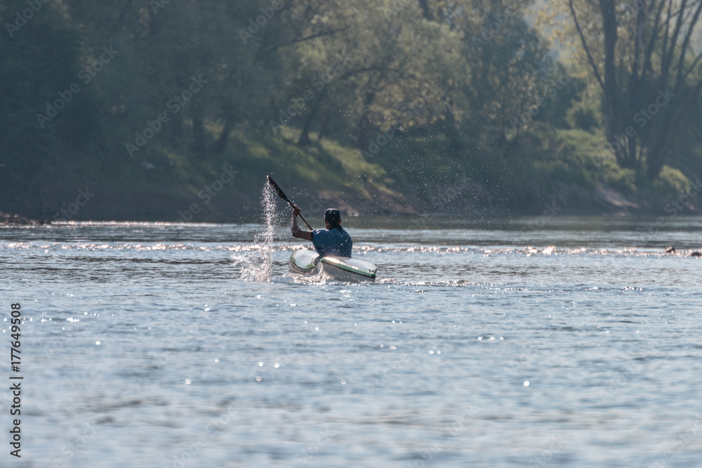 Naklejka premium atleta che se allena con la canoa, un uomo che gareggia kayak sul fiume adige, verona pescantina