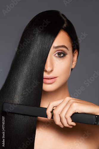 Portrait of attractive woman with straight hair on gray background