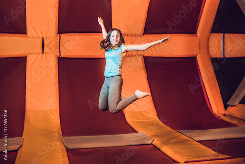 Fotografie Young woman sportsman jumping on a trampoline in fitness park and doing exersice