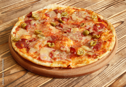 Fresh hot pizza with sausages on wooden plate
