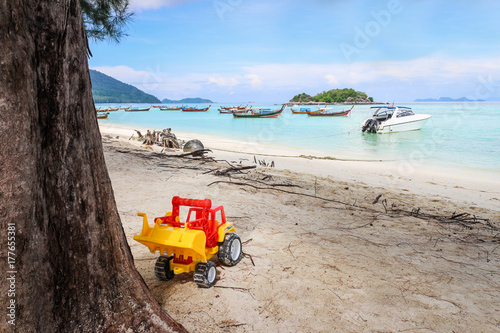 Toy car under the tree on Lipe island with boat parking in the background