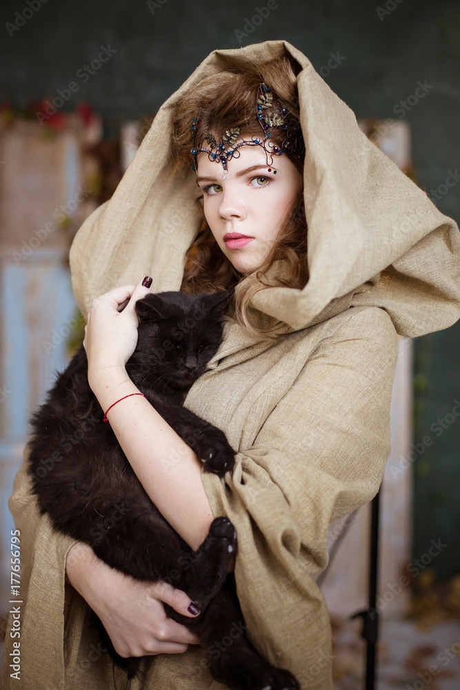 Portrait of a young, beautiful girl, woman. Holds a black cat. Kind sorceress, psychic. A wizard student, a witch is a teenager. Portrait of a young, beautiful girl, woman. Holds a black cat. Kind sorceress, psychic. A wizard student, a witch is a teenager.