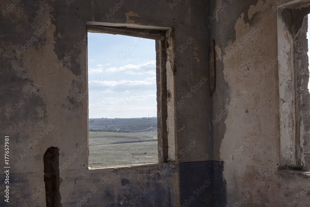 A window inside the ruins of an old abandoned house, looking on the countryside.
