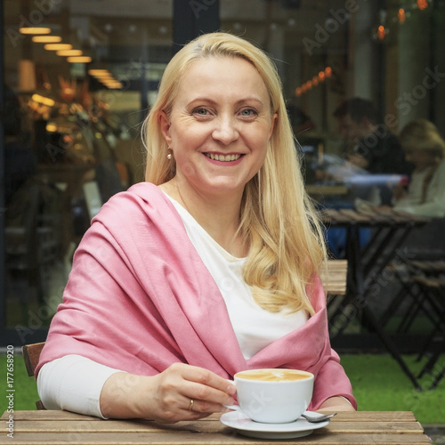 Smiling beautiful woman 45 years old drink coffee in a cafe. photo