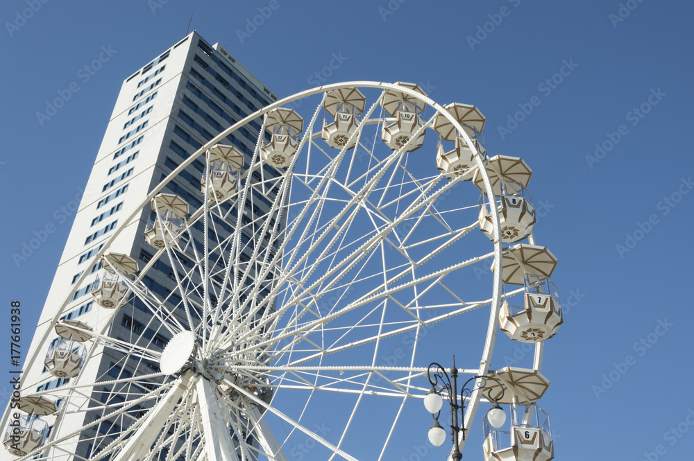 Fototapeta premium Panoramic ferris wheel with skyscraper on background