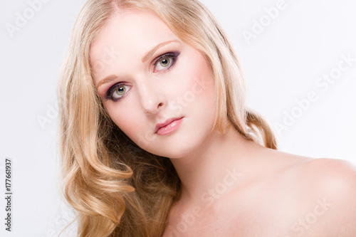 Portrait einer hübschen blonden jungen Frau mit geneigtem Kopf vor weissem Hintergrund