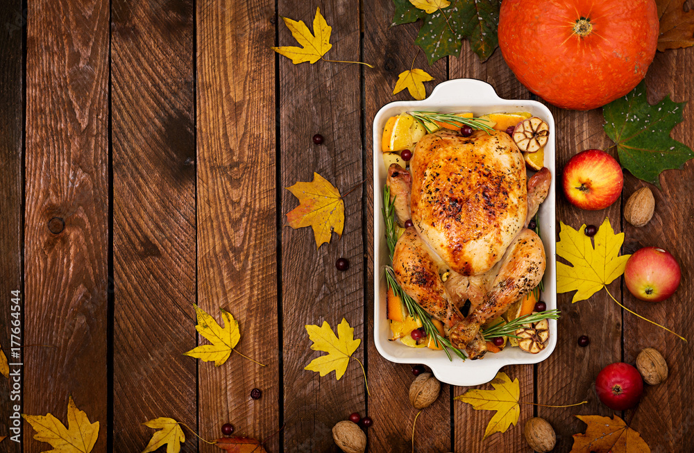 Roasted turkey garnished with cranberries on a rustic style table decorated with pumpkins, orange, apples and autumn leaf. Thanksgiving Day. Flat lay. Top view Roasted turkey garnished with cranberries on a rustic style table decorated with pumpkins, orange, apples and autumn leaf. Thanksgiving Day. Flat lay. Top view
