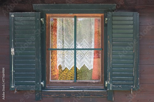 Window in the old style with open shutters and openwork curtains inside.