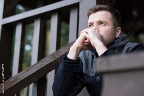 A young man sits on the street and thinks about problems. He is in constant stress.