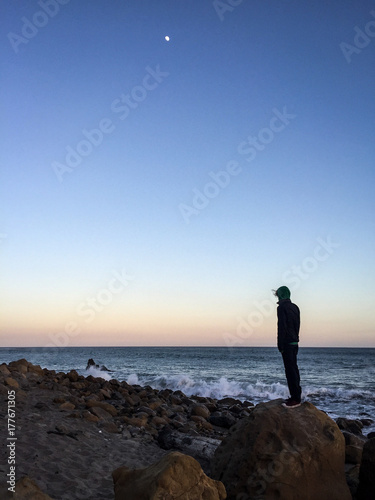 man standing on a rock at the ocean