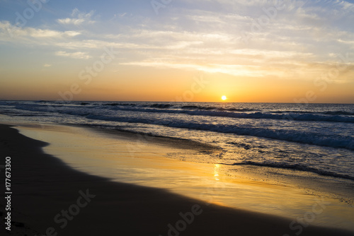 Sunset at the beach with the sun reflecting orange and yellow in the water. © sotavento1000