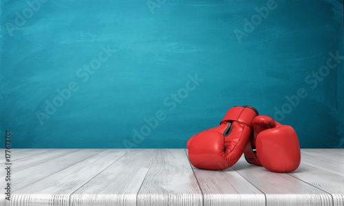 Photography 3d rendering of two red boxing gloves lying on a wooden desk in front of a blue blackboard background