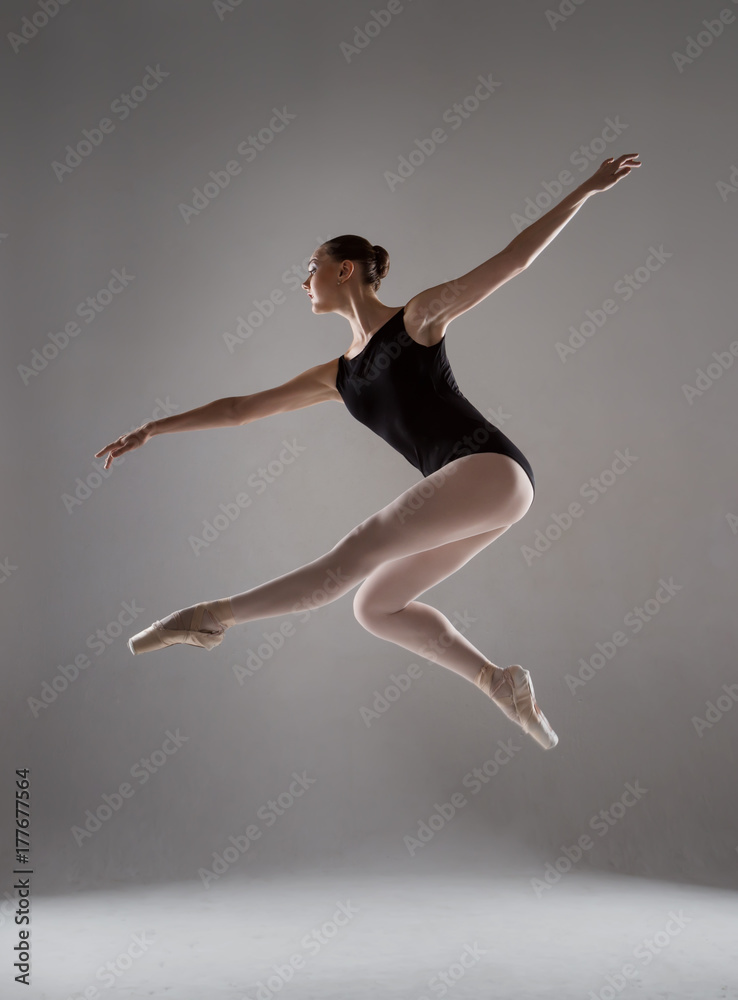 Elegant ballerina in black tights and pointes soars in the air