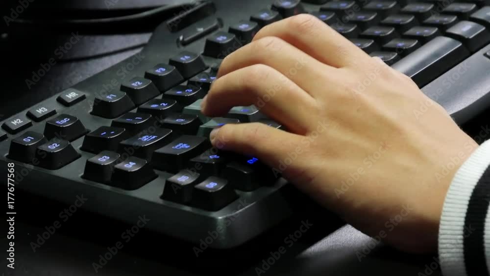 Man hands playing on a gaming computer keyboard. Keyboard with green-blue light. Neon light. Man hands playing on a gaming computer keyboard. Keyboard with green-blue light. Neon light.