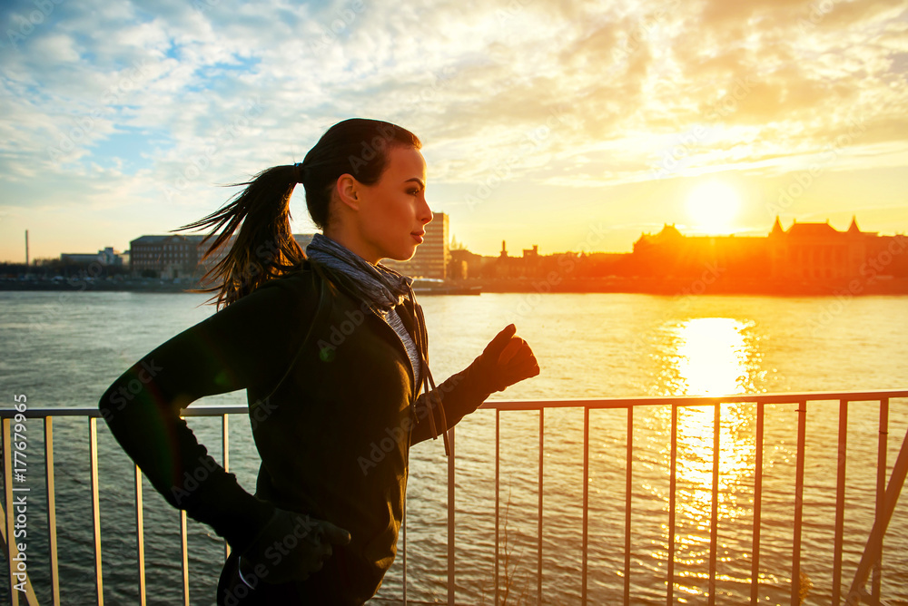 Fototapeta premium Young woman running in sunset