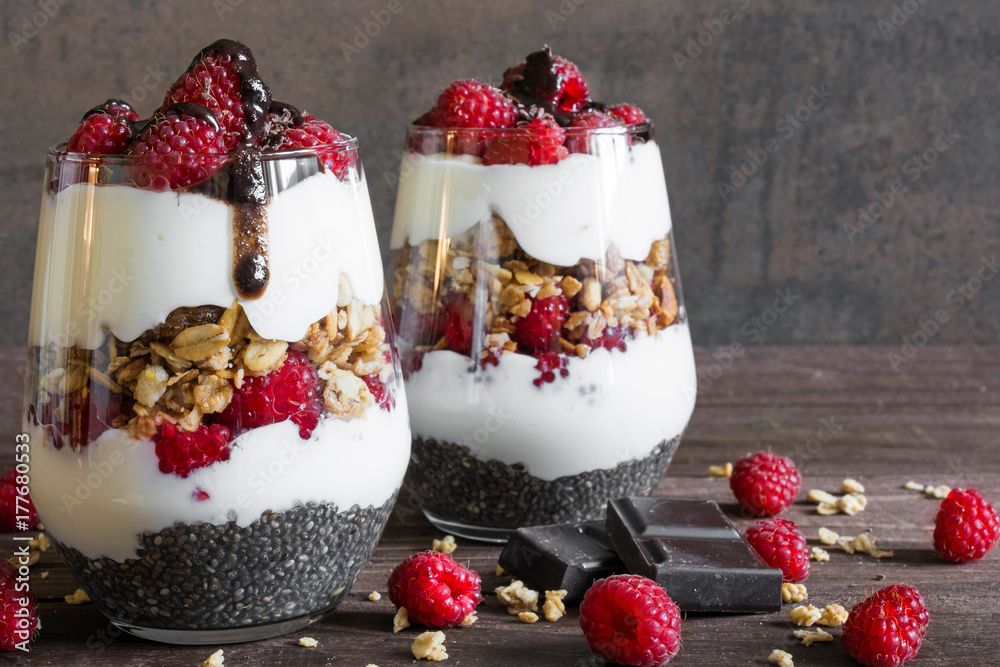 raspberry yogurt parfait in glasses with chocolate, granola and chia seeds