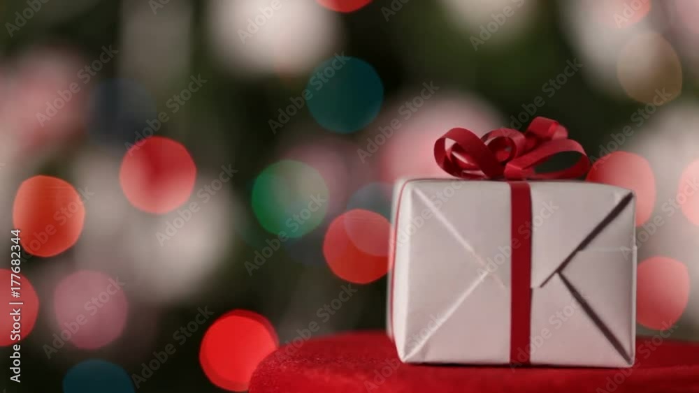 Christmas present spinning in front of blurry xma s lights and tree - closeup with copy space Christmas present spinning in front of blurry xma s lights and tree - closeup with copy space