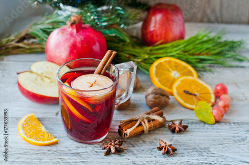Mulled wine and fruit, Christmas decor on a wooden background. Celebratory cocktail in a glass glass. Close-up