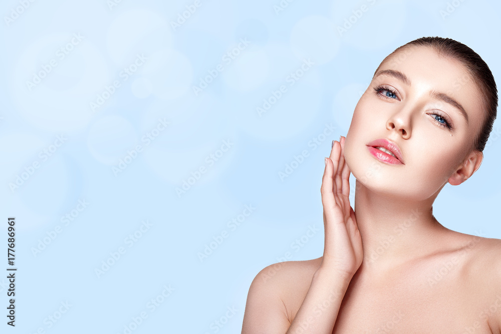 Naklejka premium Beautiful woman portrait on blue background with fresh clear nude make up, healthy skin, skin care.