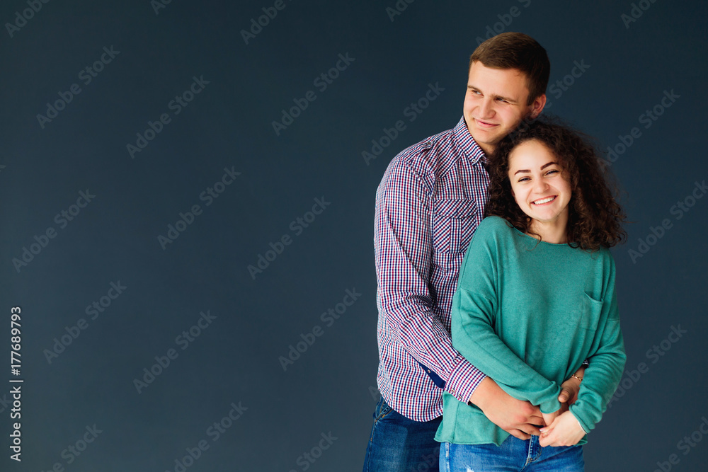 guy hugging his girlfriend from behind against plain background guy hugging his girlfriend from behind against plain background