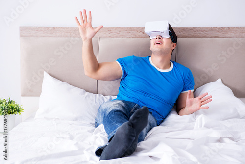 Young man in bed wearing a vr virtual reality head set