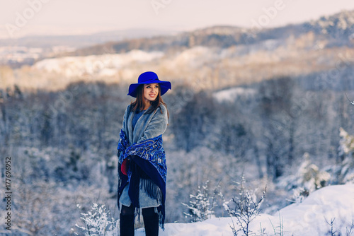 Young beautiful stylish girl in the park on the background of snowy trees. Girl in winter forest.