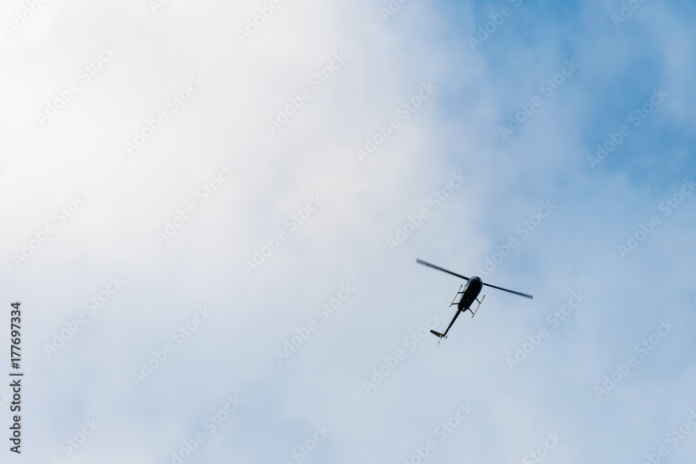 The helicopter on the blue sky with clouds