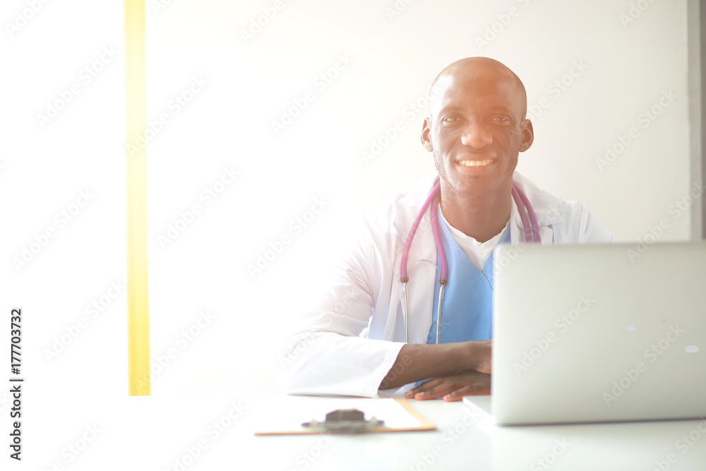 Portrait of young male doctor wearing headset while using computer at desk in clinic. Doctor. Portrait of young male doctor wearing headset while using computer at desk in clinic. Doctor.