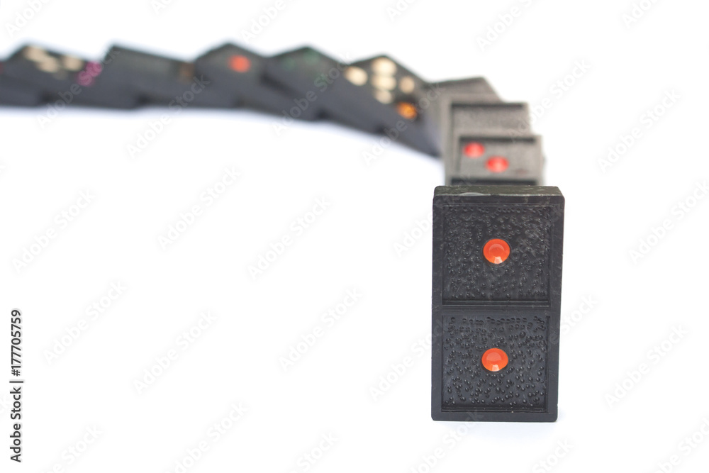 Fototapeta premium Row of old black color dominoes with colorful dot pieces on white floor background.