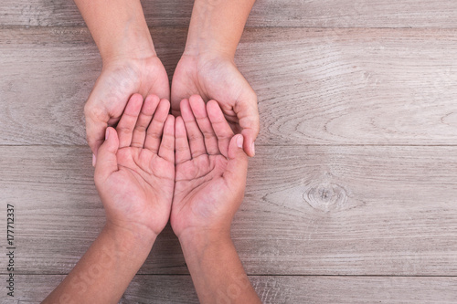 Help and support Concept : Woman holds her young kids hands on brown wooden table. Free space for text or design