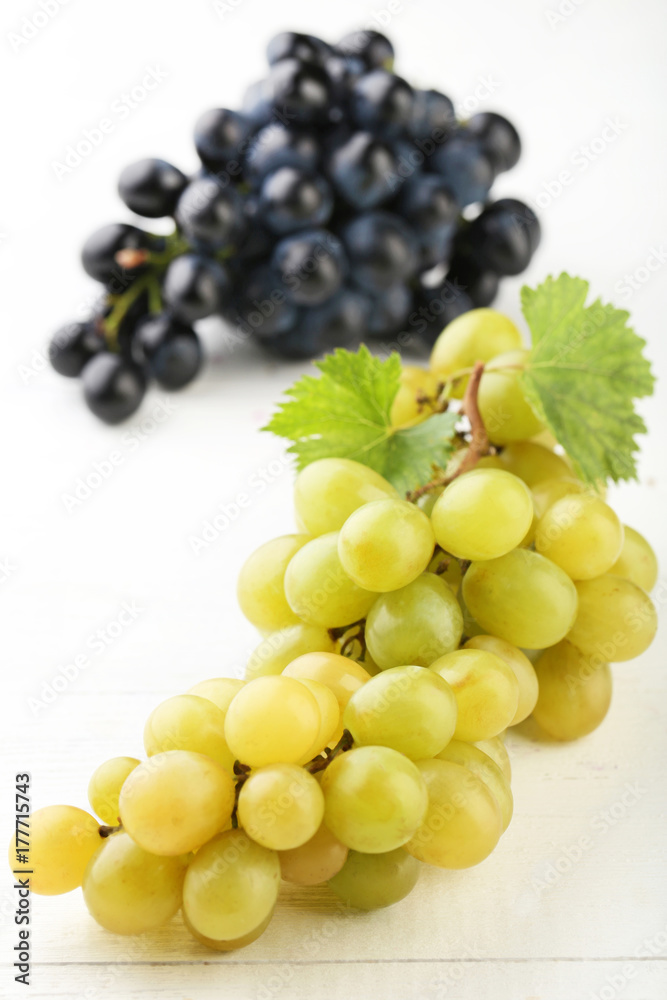 Green and blue grapes on white wooden table