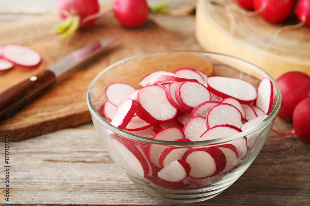 Sliced red radish in bowl on grey wooden table Sliced red radish in bowl on grey wooden table