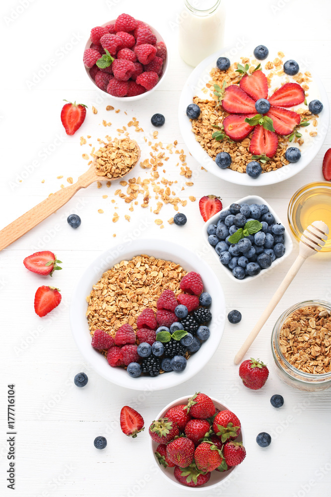 Granola with berries in plate and honey on white wooden table Granola with berries in plate and honey on white wooden table